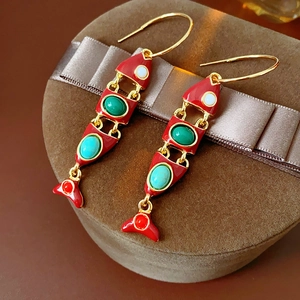 Vue macro détaillée de boucles d'oreilles poisson vintage avec pierres colorées et métal doré