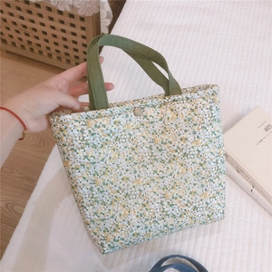 Close-up of floral bento bag with green canvas handles and metal snap button closure