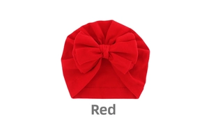 Detail view of red baby turban hat with a large bow made from soft elastic cotton blend