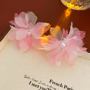 Detail of pink gradient mesh flower hair clip with a center pearl on a vintage book