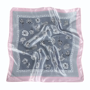 Detail of silk satin square scarf with gray floral pattern and pink border in soft folds