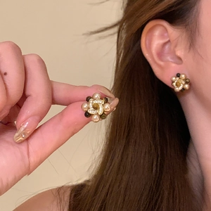 Detail von blumenförmigen Ohrringen mit Goldbeschichtung, Perlen und Zirkonia am Modell