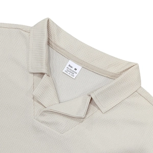 Detalle del cuello de polo y etiqueta de talla en la camisa beige de punto waffle de manga corta