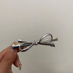 Detailed view of a silver metallic bow hair clip with a smooth mirror finish