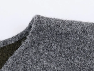 Close-up of thick knitted fabric texture in grey and dark green mixed wool blend fiber