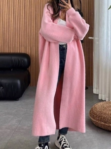 Détail d'un long gilet en maille pelucheuse rose avec une coupe décontractée et douce
