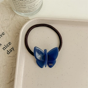 Detailed macro view of a jelly-textured blue butterfly hair tie on a ceramic tray