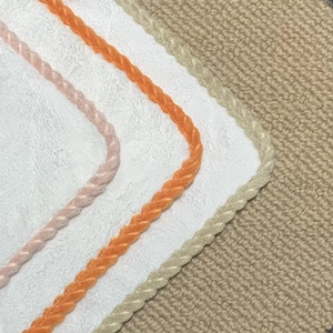 Detail of coral fleece towel showing colorful rope edging and soft tulip embroidery texture