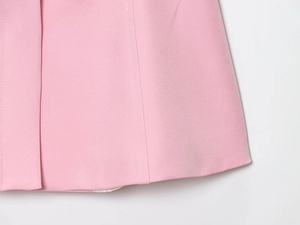 Vista macro del tessuto rosa liscio e cuciture precise sull'orlo dei pantaloni a campana