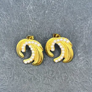 Retro 18k gold plated feather earrings with elegant white pearls on a stone background