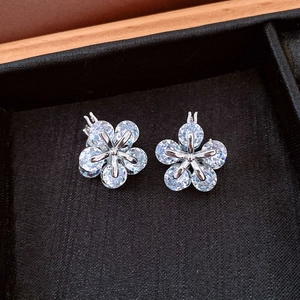 Vue macro de boucles d'oreilles fleur en argent avec zircone dans un coffret noir