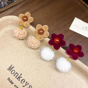 Detail of floral velvet stud earrings with soft plush pompom pendants in warm autumn tones