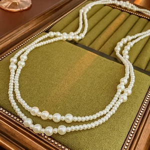 Detail of vintage double-layer pearl necklace with varied bead sizes on green velvet