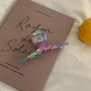 Detail of a marble textured hair claw clip with colorful resin swirls on a book