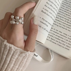 Anillo de racimo de perlas de latón plateado usado por modelo sosteniendo un libro