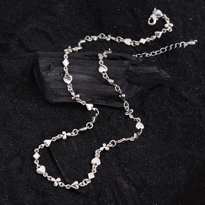 Silver card suit necklace with heart, butterfly and diamond charms on black background