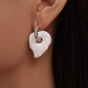 Macro shot of silver textured hoop earring with white organic shaped drop pendant
