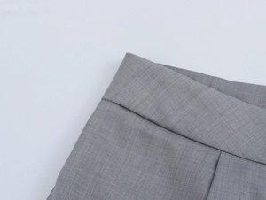 Gros plan sur la taille plissée grise et la texture tissée du pantalon droit élégant