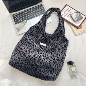 Flat lay of leopard print tote bag with laptop and accessories on white background