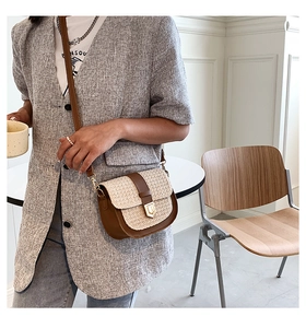 Detail of vintage beige straw saddle bag with brown leather trim and gold metal clasp