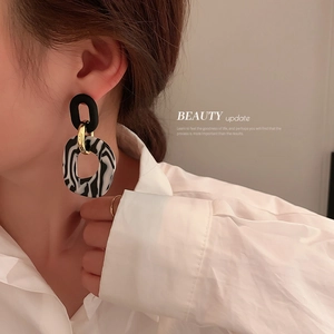 Detail view of zebra print hoop earrings with black matte and gold metal accents