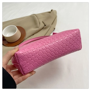 Close-up of pink woven texture handbag held by hand in a cozy lifestyle setting