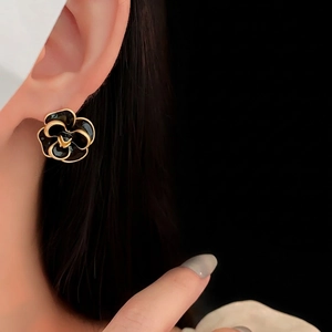 Vintage black camellia earrings with gold edges shown on a model's ear lobe