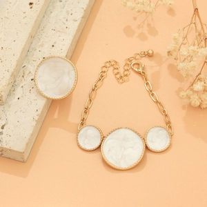 Detail showing vintage gold chain bracelet with white marble textured charms and lobster clasp
