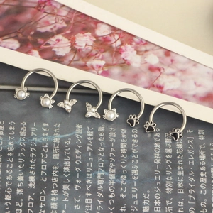 Silver stainless steel butterfly and cat piercing rings set with pearls on magazine