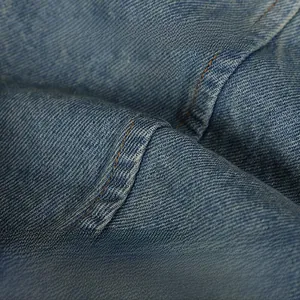 Macro shot of soft washed denim fabric with detailed twill texture and faded blue finish