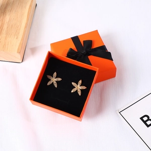 Starfish gold earrings with small diamonds in an orange gift box with black ribbon bow