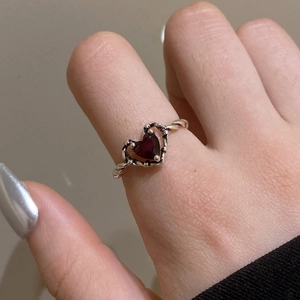 Macro shot of punk gothic silver ring featuring a dark red heart gem and rope texture