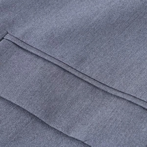 Gros plan sur la texture sergé gris et les doubles coutures précises de la poche veston