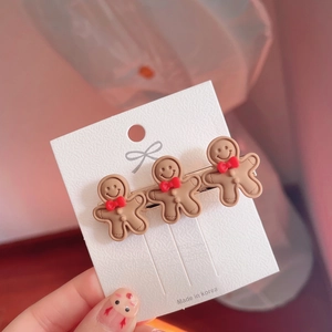 Detail showing three brown gingerbread man hair clips with red bows on a card