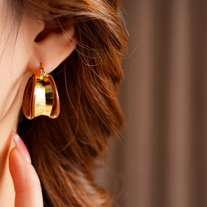 Détail d'une boucle d'oreille en C plaquée or avec incrustation de résine ambre sur modèle