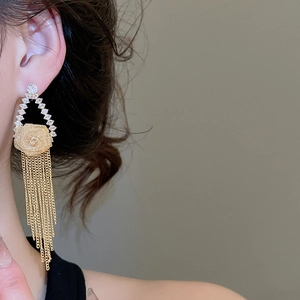 Macro shot of gold-plated flower stud earrings with cascading fringe tassels and zircons