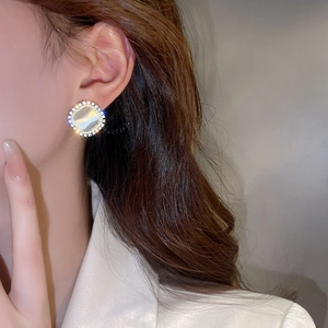 Close-up of gold-plated square cat's eye earrings with shimmering zircon border