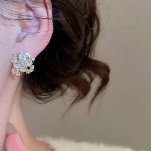 Close-up of sparkling flower stud earrings with crystals on a model's ear