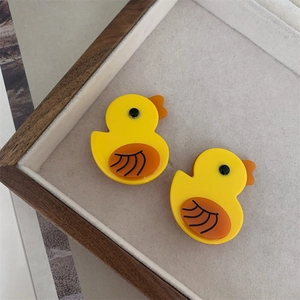 Detailed view of two cute yellow duck hair clips on a grey velvet display tray