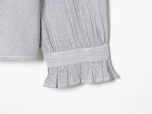 Detail of long sleeve cuff with vertical stripes and elastic ruffled frill edge
