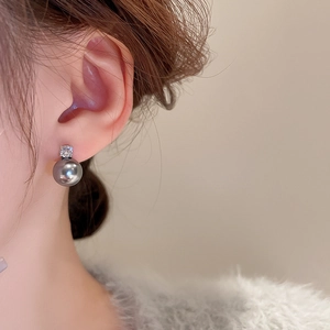 Close-up of elegant grey pearl stud earring with sparkling zircon on a model's ear