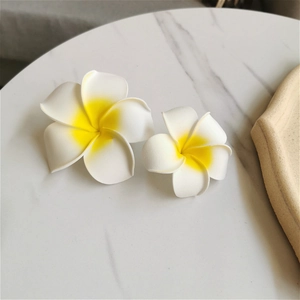 Detail view of realistic white plumeria flower hair clips on a marble texture surface