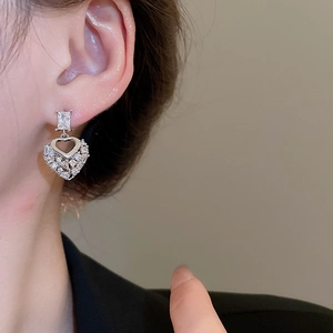 Close-up of heart-shaped silver earrings with sparkling cubic zirconia on model