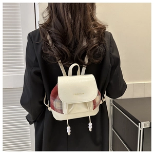 Detail eines Vintage-Rucksacks in Beige mit roten Karomustern und Mode-Schriftzug