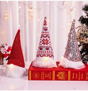 Close-up of three glowing Christmas gnomes with sequins and knit hats on vintage books