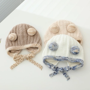 Close-up of knit baby hats with plush earflaps and cute pom-poms in various colors