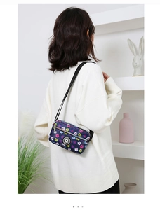 Floral nylon crossbody bag in navy blue shown on a model in a modern home setting