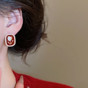 Close-up of vintage oval pearl earrings with red enamel and white tulip relief design