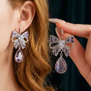 Elegant palace style bow earrings with purple teardrop zircon and silver finish