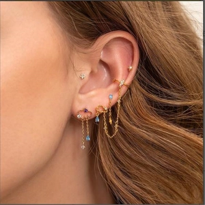 Detail of gold floral ear cuff set with blue and purple gemstones on model's ear